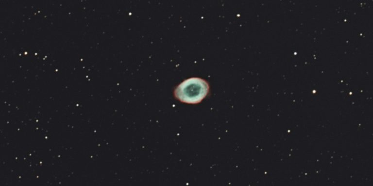 Der Ringnebel M57 - der Überrest eines Sterns. Man kann die übriggebliebene Gashülle erkennen, in grünblau mit einem roten Rand.
