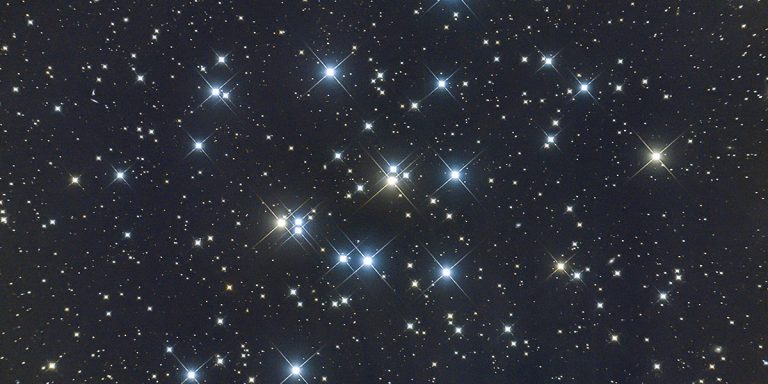Der offene Sternhaufen M44. Die Sterne leuchten hell in gelb und blau und es scheint, als würden sie wie Diamanten funkeln.