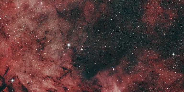 NGC7000 - der Nordamerikanebel. Rote Nebelwolken scheinen durch den Weltraum zu schweben. Man kann zwischen den Nebelschwaden in den Weltraum blicken.