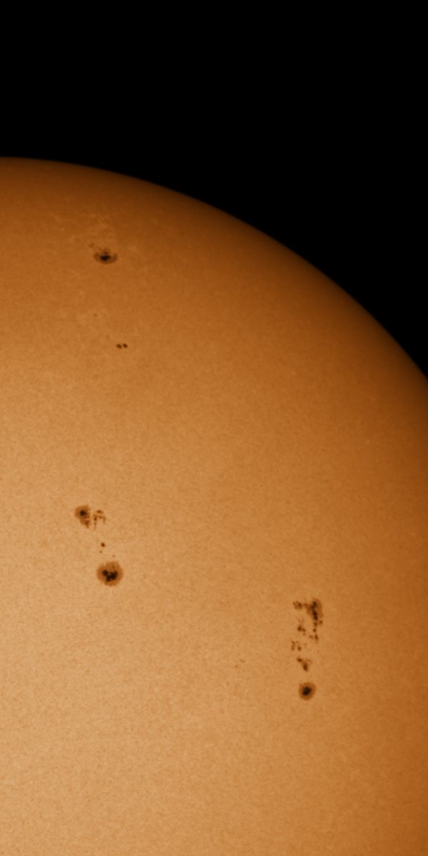 Eine Vergrößerung der Sonnenflecken. Diese heben sich optisch deutlich von der hellorangen Oberfläche als dunkelbraune Flecken ab.